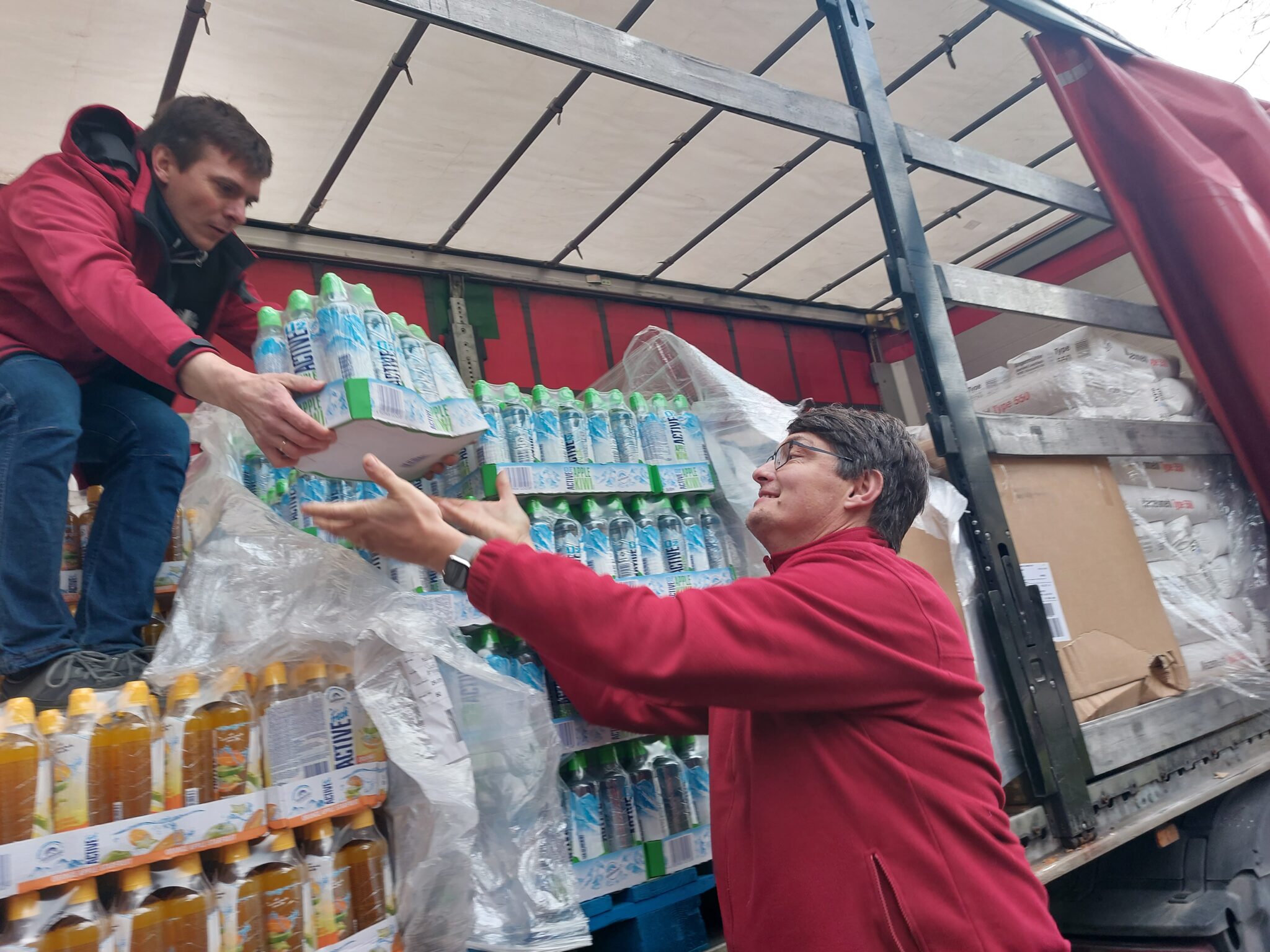 Dobrovoľníci spoločne vykladajú humanitárnu pomoc
